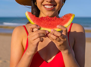 donna che mangia un'anguria fresca all'aperto per la dieta estiva